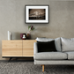Framed and mounted photograph of Albert Bridge on the river Thames in South West London hanging on a wall above a sofa and cupboard