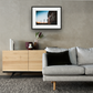 Framed and mounted photograph of Arsenal's Emirates Stadium in North London above a sofa and a cupboard.