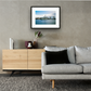 Framed and mounted photograph of hms belfast battleship on the river thames on southbank in the city of london hanging on a wall above a sofa and cupboard