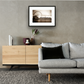 Framed and mounted photograph of London Eye & County Hall on the river Thames in central London hanging on a wall above a sofa and cupboard