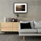 Framed and mounted photograph of Millennium Bridge and St Pauls Cathedral on the river Thames in the city of London hanging on a wall above a sofa and cupboard