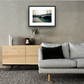 Framed and mounted photograph of putney bridge on the river thames in south west london hanging on a wall above a sofa and cupboard