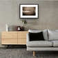 Framed and mounted photograph of Tower Bridge & Tower of London on the river Thames in central London hanging on a wall above a sofa and cupboard